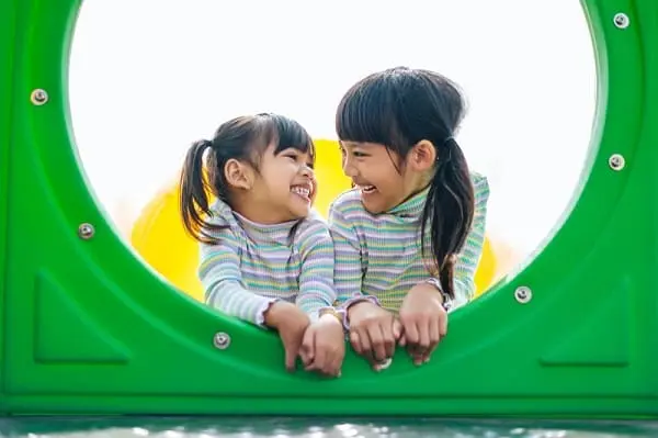 dua anak perempuan bermain di taman bermain dengan senang